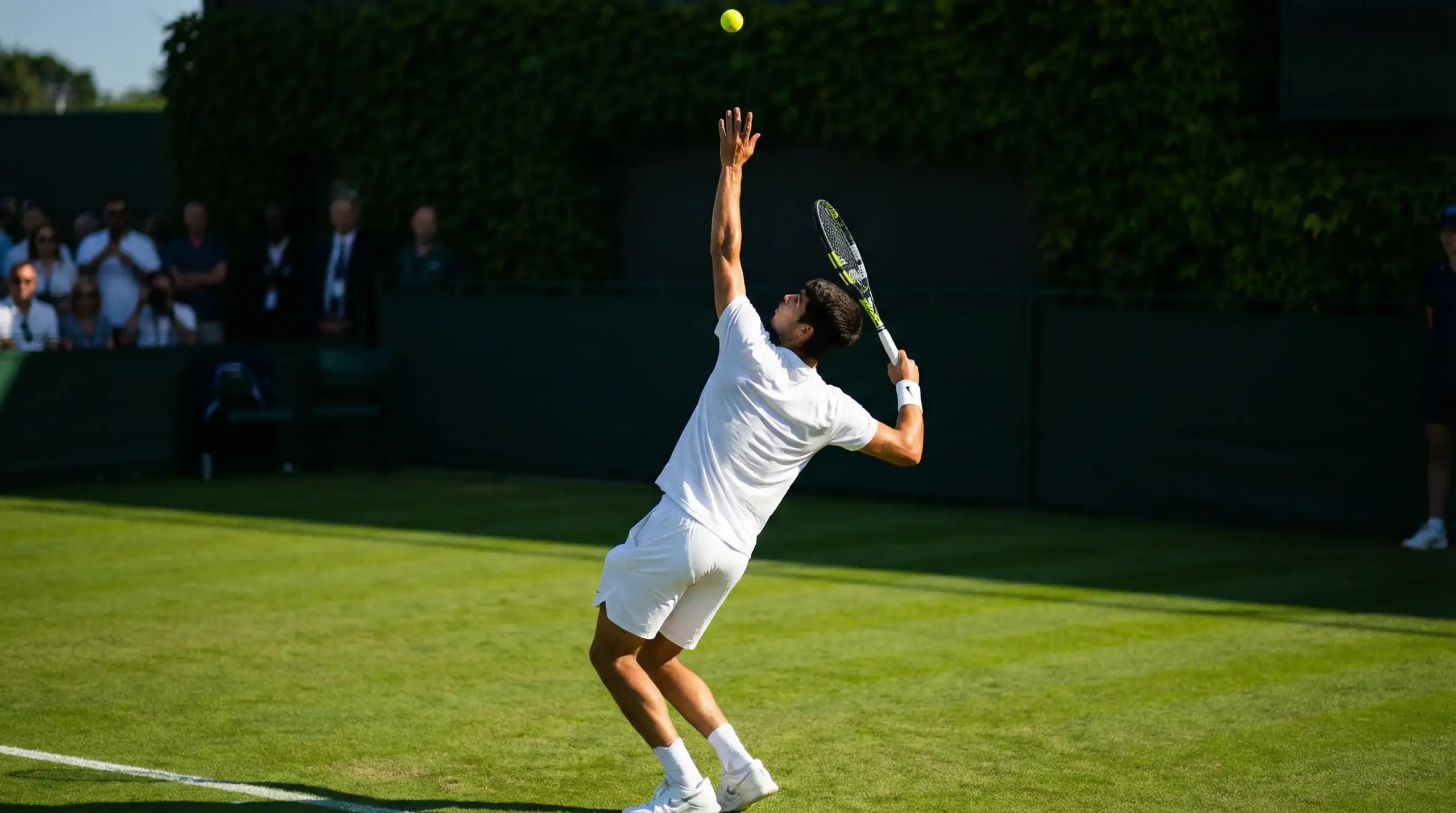 Jugador de tenis sacando en la pista central de Wimbledon al inicio de un partido bajo el sol