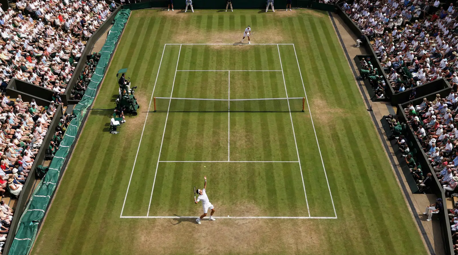 Vista cenital de una pista de hierba de Wimbledon durante un partido de tenis con las gradas llenas de espectadores